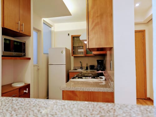 Cocina moderna y comedor en el apartamento Casa Donceles en Ciudad de México, con gabinetes de madera, encimera de granito y