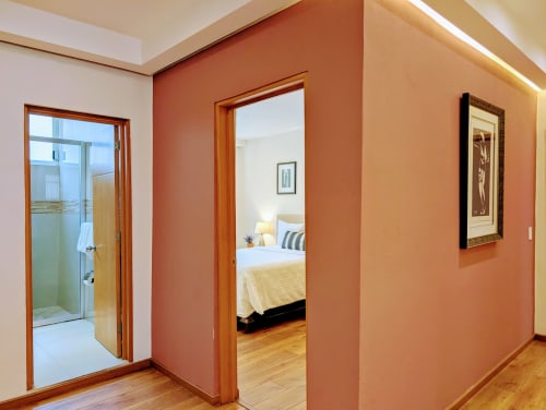 Pasillo con paredes de barro, puertas de madera, entrada de baño y vista al dormitorio en el departamento Casa Donceles en Ciudad de México