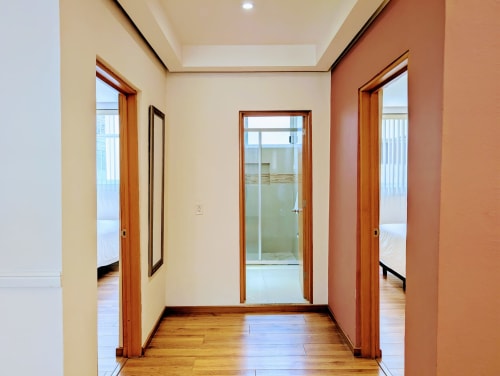 Pasillo moderno del apartamento Casa Donceles en Ciudad de México con puertas de madera, paredes crema y terracota, y pisos de madera