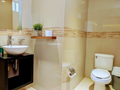 Baño moderno en Casa Donceles, apartamento en Ciudad de México con lavamanos blanco, inodoro, ducha y paredes con azulejos crema