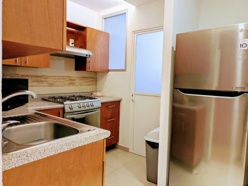 Cocina moderna del apartamento Casa Donceles con electrodomésticos de acero inoxidable, encimeras de granito y gabinetes de madera en México
