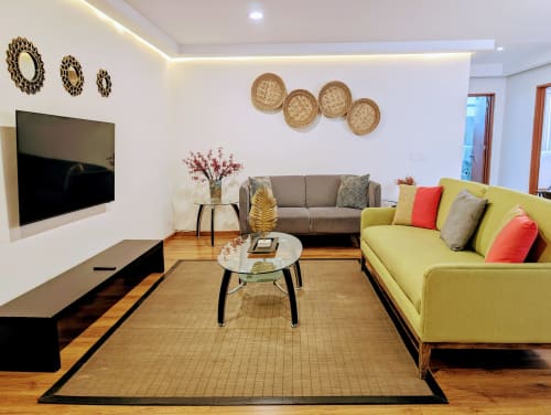 Sala moderna en Casa Donceles de la Ciudad de México con sofás gris y amarillo, TV montada en pared y cesta decorativa
