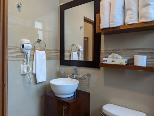 Baño moderno del apartamento Casa Donceles en Ciudad de México con lavamanos blanco redondo, espejo con marco negro, estantes de madera