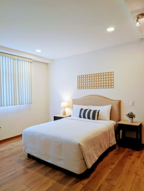 Dormitorio luminoso en apartamento Casa Donceles de la Ciudad de México con cama queen, mesitas de noche, piso de madera y persianas verticales