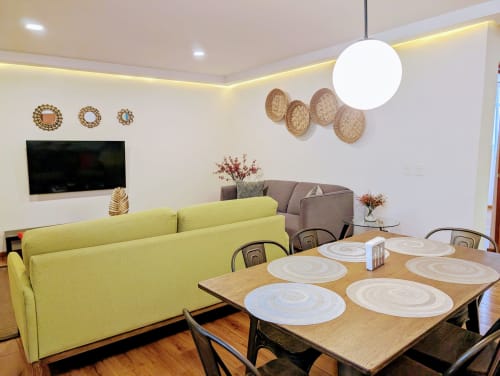 Área moderna de comedor y sala de estar en Casa Donceles con sofá amarillo, mesa de madera y decoración de pared en México