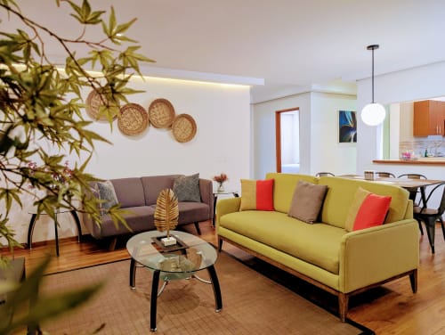 Sala de estar moderna en Casa Donceles, Ciudad de México con sofás amarillos y grises, mesa de vidrio, canastas decorativas y cocina