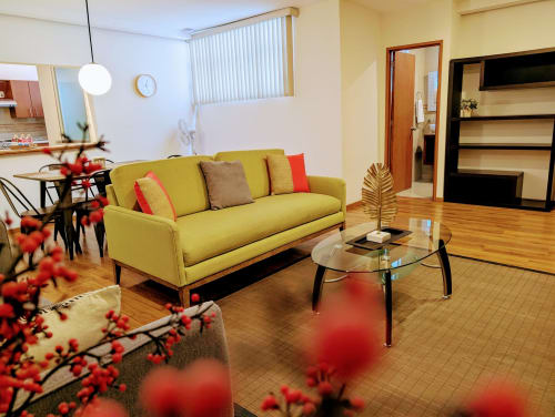 Sala de estar luminosa del apartamento Casa Donceles en Ciudad de México con sofá amarillo, mesa de centro de cristal y mobiliario moderno