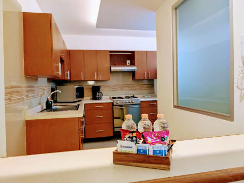 Área de cocina del apartamento Casa Donceles en Ciudad de México con gabinetes de madera, estufa de acero inoxidable y amenidades de bienvenida