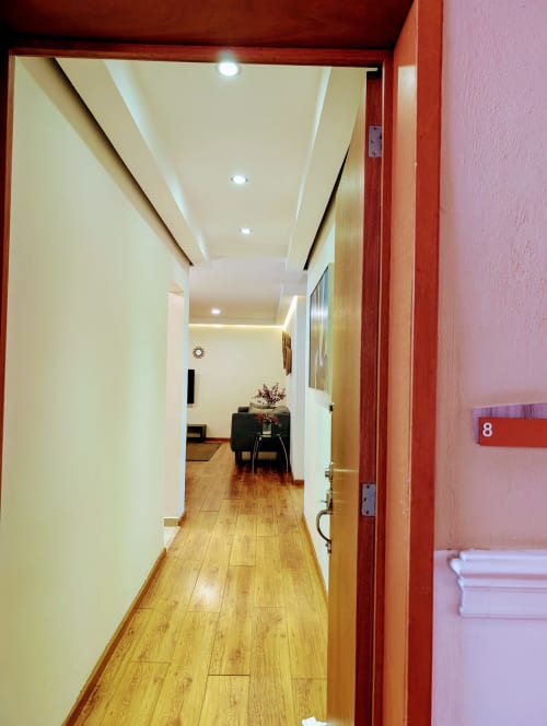 Pasillo moderno del apartamento 8 Casa Donceles con suelos de madera, paredes color crema e iluminación empotrada hacia el salón