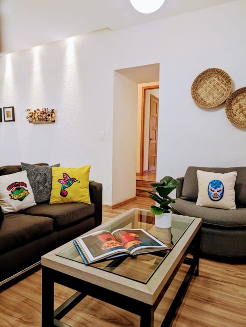 Sala de estar moderna del penthouse Casa Donceles en Ciudad de México con sofás negros, almohadas coloridas y mesa de centro de madera
