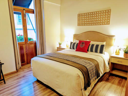 Dormitorio luminoso en el penthouse Casa Donceles de la Ciudad de México con cama de madera, vistas de la ciudad a través de puertas francesas y decoración moderna.