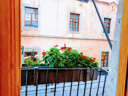 Balcón colorido con flores rojas con vista al patio histórico de Casa Donceles, Ciudad de México