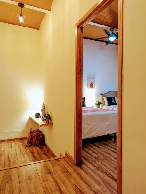 Entrada del pasillo al dormitorio del penthouse Casa Donceles en México, con paredes amarillas y piso de madera