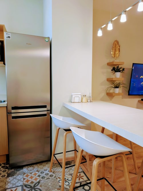 Área de cocina moderna en el penthouse Casa Donceles con refrigerador de acero inoxidable, encimera blanca y taburetes de madera