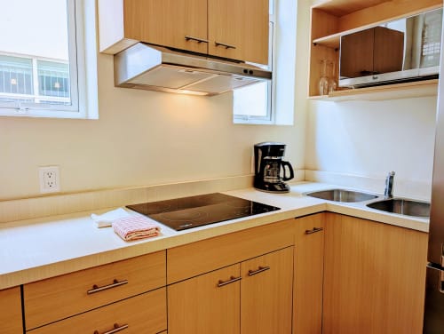 Cocina moderna en penthouse Casa Donceles con gabinetes de madera, encimeras blancas, estufa de inducción y acero inoxidable
