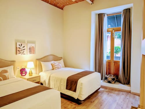 Habitación luminosa en Casa Donceles en la Ciudad de México con camas gemelas, muebles de madera, vistas de la ciudad a través de puertas francesas y