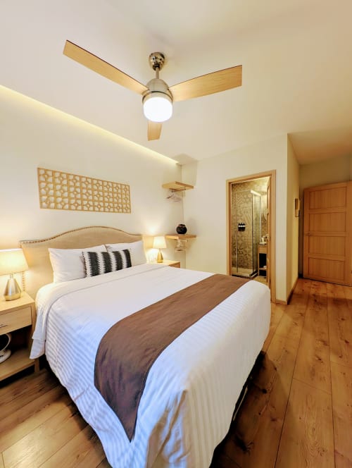 Habitación moderna del hotel Casa Donceles en Ciudad de México con ventilador de techo de madera, ropa de cama blanca y piso de madera
