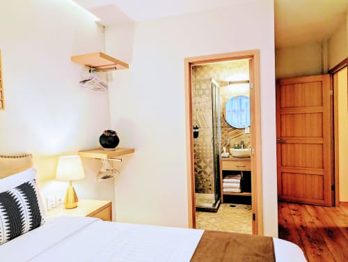 Recámara moderna del hotel Casa Donceles en la Ciudad de México con estantes de madera, lámpara y entrada al baño privado