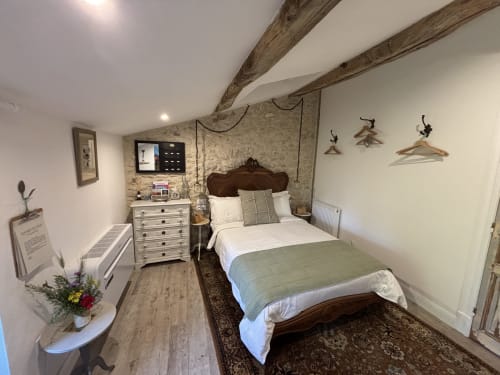 La Chambre Jardin à la Maison Mûrier à Fayssac avec lit en bois, tête de lit marron, poutres apparentes et décoration rustique