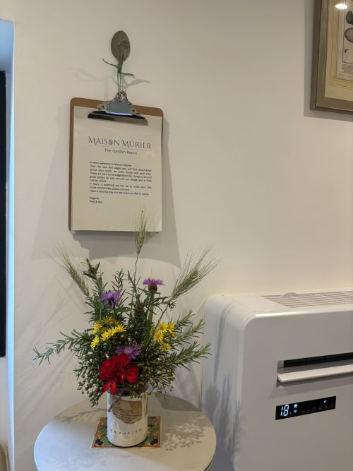 Lettre de bienvenue de la Maison Mûrier avec un arrangement floral coloré et des épis de blé décoratifs sur une petite table