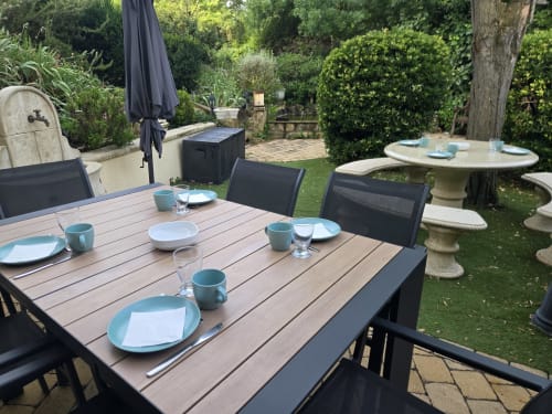 Table à manger extérieure du Domaine à l'Aise B&B à Saint-Pargoire, dressée avec de la vaisselle bleue et entourée de végétation luxuriante