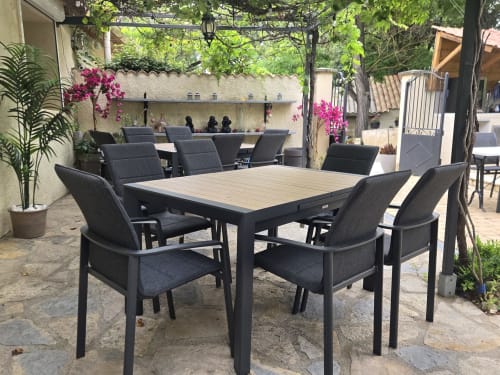 Terrasse de restaurant en plein air du Domaine à l'Aise avec table et chaises noires, fleurs magenta éclatantes