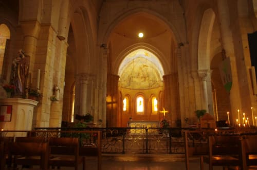 Intérieur d'église historique avec arches ornées, bancs en bois et éclairage doré à Saint Germain et Mons, Aquitaine