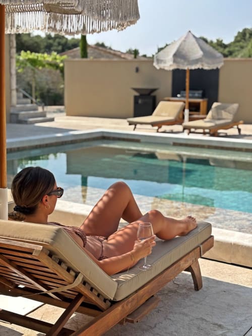 Mujer relajándose en una tumbona junto a la piscina climatizada de la villa La Maison D'ambrine en Chamaret, Francia