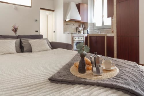 Modernes Studio in Mailand mit Bett, Kochnische und Frühstück mit Croissants und Kaffee auf dem Tisch