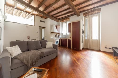 Modernes Mailänder Apartment mit Holzbalken, grauem Sofa, ausgestatteter Küche und Parkettboden