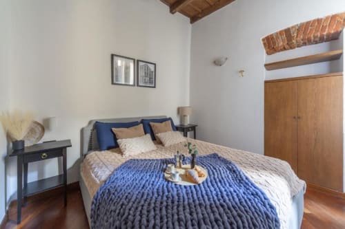 Gemütliches Schlafzimmer in Mailänder Wohnung mit blauen Akzenten, Holzkleiderschrank und Parkettboden in den Magnolia Apartments