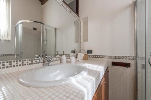 Modernes Badezimmer mit rundem weißem Waschbecken, Mosaikdetails und großem Spiegel in Magnolia Apartments Milan