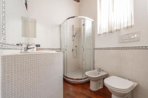 Modernes Badezimmer in den Magnolia Apartments Mailand mit Dusche, Bidet, Toilette, kleinem Waschbecken, Spiegeln und Fliesenwänden