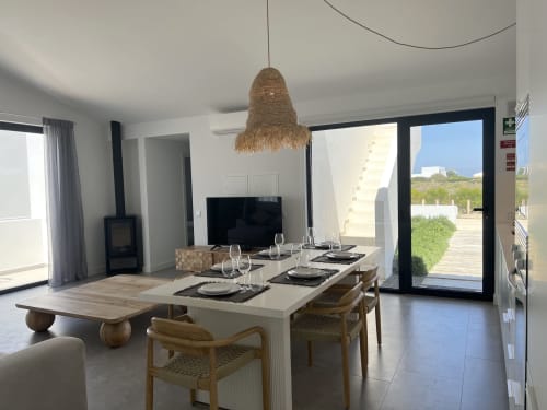 Área de jantar da moderna villa Star Host Casa Tonel em Bordeira com vista para o mar, móveis contemporâneos e acesso à varanda