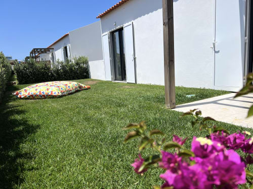 Villa Casa Tonel na Star Host em Bordeira, com gramado exuberante, almofadas coloridas ao ar livre, paredes brancas e flores rosa-choque