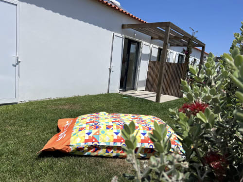 Almofada colorida no pátio gramado da villa Casa Tonel em Bordeira com pérgola e vista para o mar