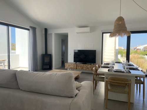 Sala de estar moderna da Casa Tonel em Bordeira com vista para o mar, mobiliário confortável e zona de refeições