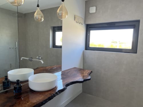 Banheiro moderno da villa Casa Tonel em Bordeira com duas cubas, bancada em madeira escura, chuveiro tipo chuva e vista para o mar