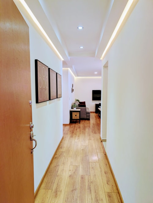 Pasillo moderno del apartamento Casa Donceles en Ciudad de México con piso de madera, obras de arte enmarcadas y vista a la sala
