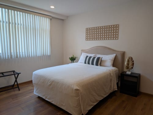 Dormitorio principal del apartamento Casa Donceles con cama queen, decoración neutral, mesita de noche y luz natural de persianas verticales