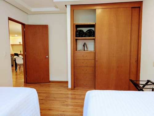 Dormitorio del apartamento Casa Donceles en Ciudad de México con dos camas, armario de madera, cómoda y puerta abierta