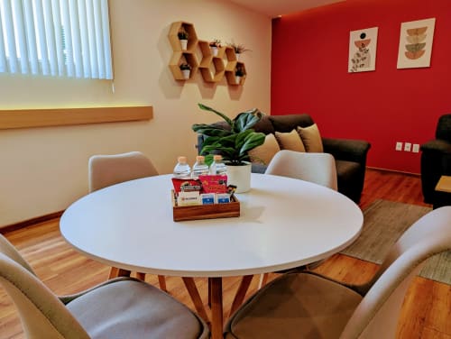 Comedor moderno en el apartamento Casa Donceles de la Ciudad de México con mesa redonda blanca, asientos cómodos y toques de rojo vibrante