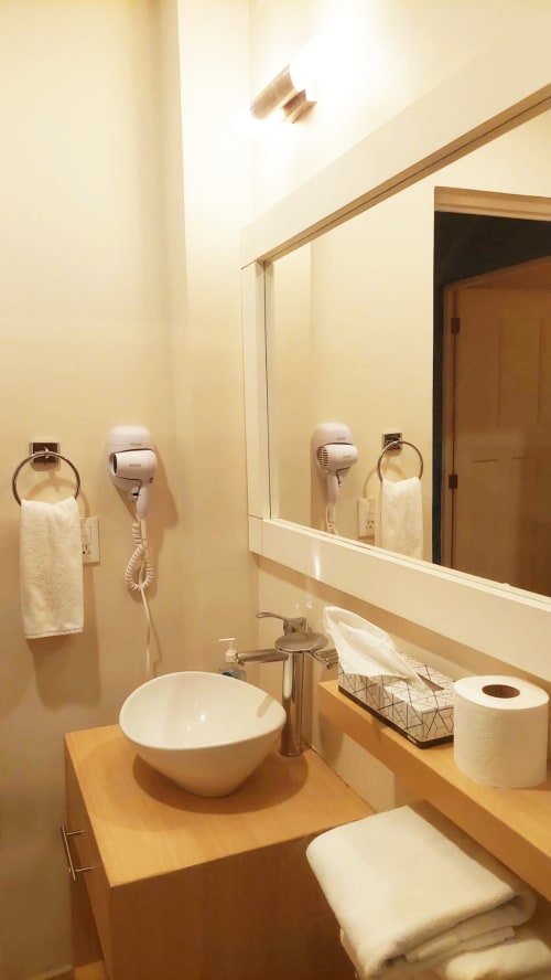Baño moderno en el hotel Casa Donceles de la Ciudad de México con lavamanos redondo blanco, espejo, secador de pelo y amenidades