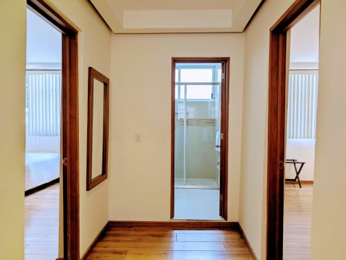 Pasillo del apartamento Casa Donceles con puertas de madera, paredes beige y piso de madera que conducen a la vista del balcón.