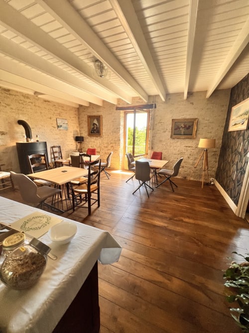 Salle à manger rustique des Logis de Kergoulou à Concarneau avec murs en pierre apparente, plafond à poutres et sols en bois