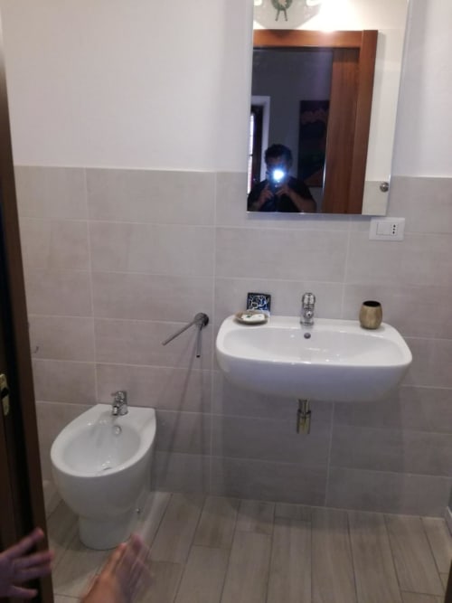 Bagno moderno di Zia Amalia Villa Asfodelo ad Alghero con lavabo bianco, bidet, specchio e pareti in piastrelle beige