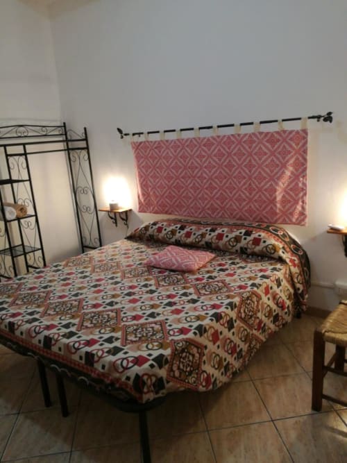 Accogliente camera da letto di Zia Amalia Villa Asfodelo ad Alghero con biancheria decorata e letto in ferro battuto