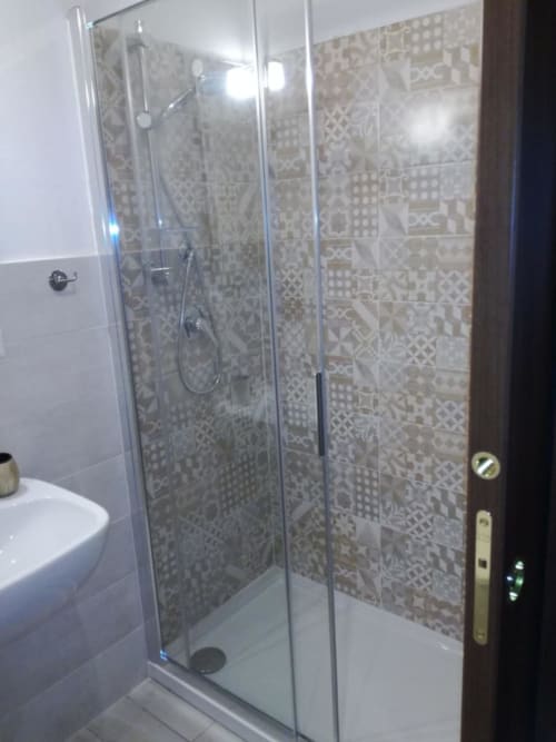 Moderno box doccia in vetro con rivestimento a piastrelle decorate nella suite da bagno di Zia Amalia Villa Asfodelo, Alghero