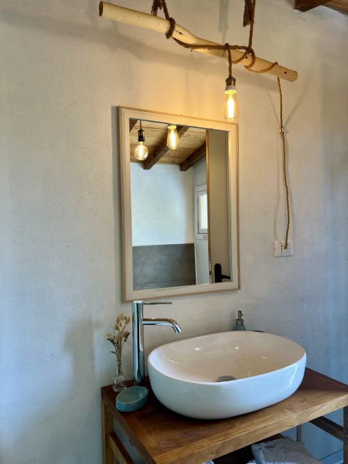 Lavabo de salle de bain moderne avec vasque blanche ovale, comptoir en bois, miroir encadré et lampes suspendues à l'Agritusmo Stecadò
