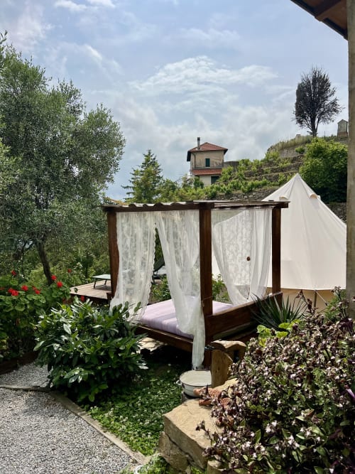 Lit baldaquin extérieur aux rideaux blancs dans le jardin italien d'Agritusmo Stecadò, Dolceacqua